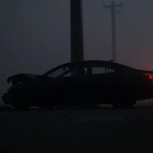 Crashed vehicle against a utility pole on a foggy night